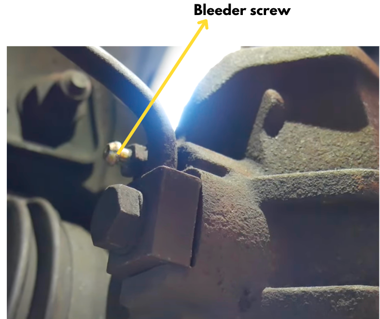 Brake-caliper bleeder screw identified by an arrow.