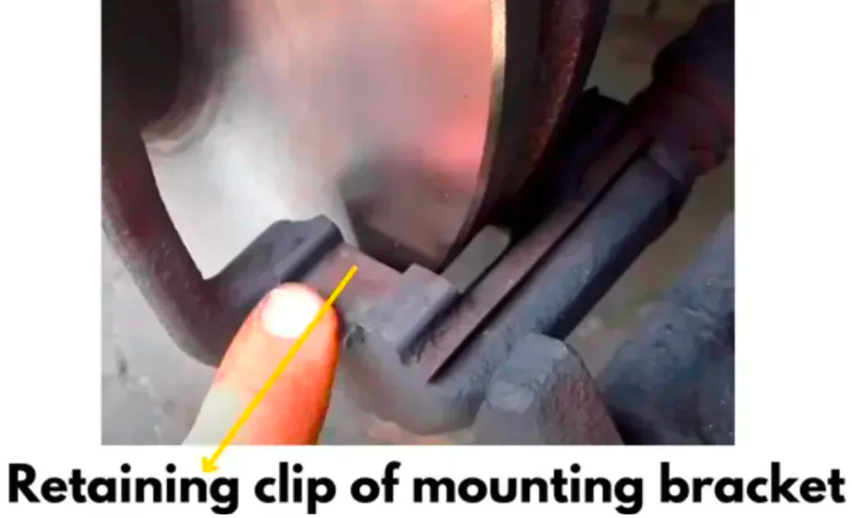 Brake-pad retaining clip on the mounting bracket, identified by an arrow.