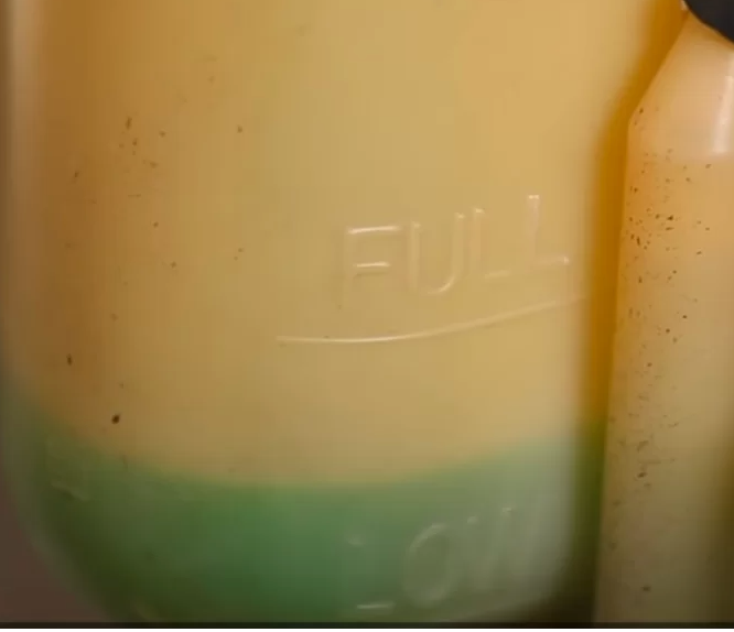 Translucent coolant reservoir showing the FULL level marking and green fluid below it.