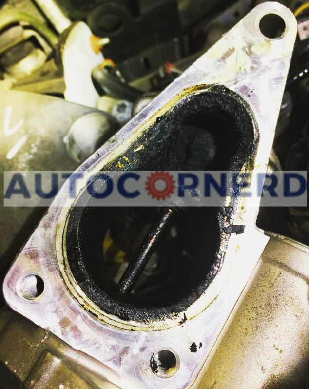 Removed EGR valve with dark deposits around its passage and valve plate.