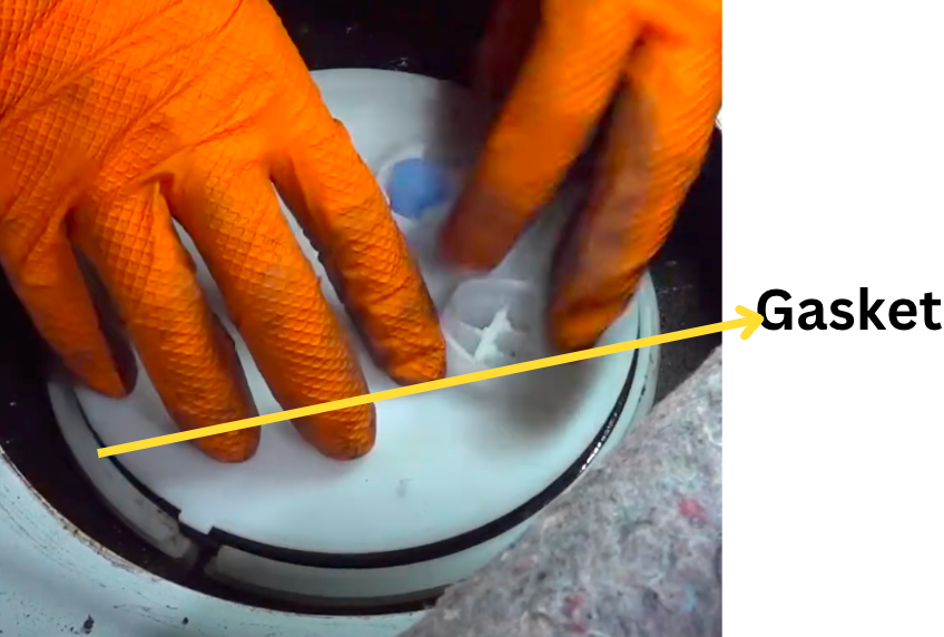 Gloved hands fitting a sealing gasket to the top of a fuel-pump assembly.