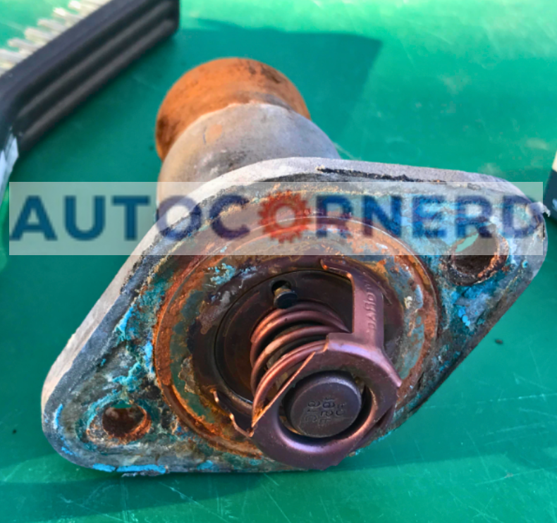 Thermostat and spring visible in a coolant housing.