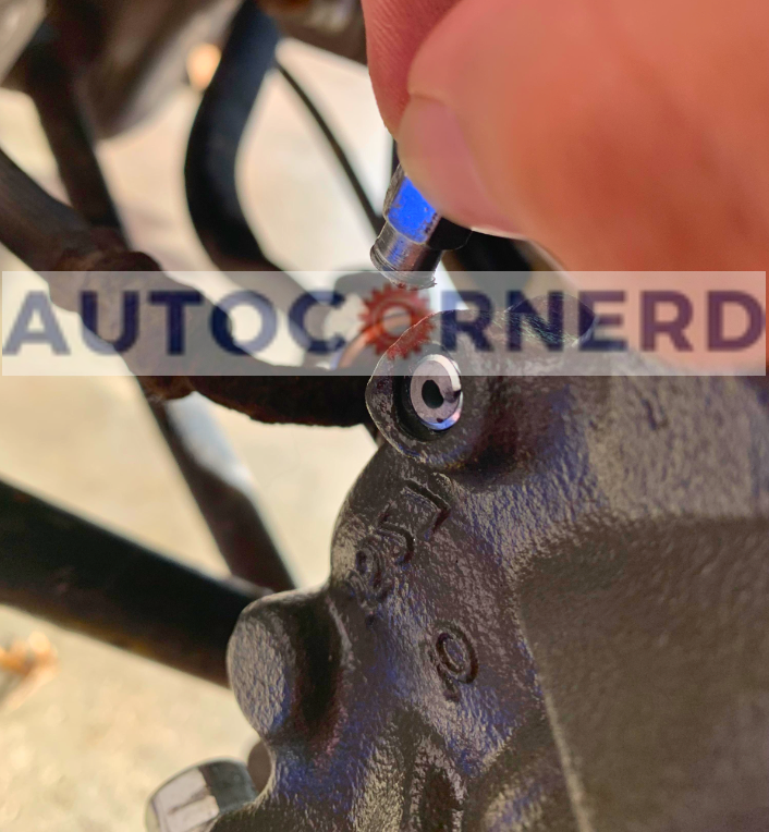 Brake-caliper bleeder valve beside the wheel area.