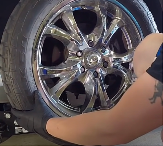 shaking the wheel with hands to inspect tie rod joints