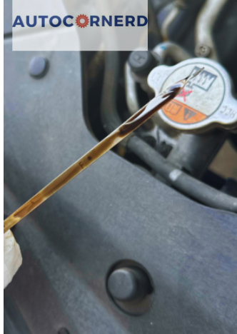 A close-up image of an engine oil dipstick being pulled out of an engine, showing dark and potentially contaminated engine oil, which could lead to rough idling or shaking on a cold start but smoother operation once the engine is warmed up.