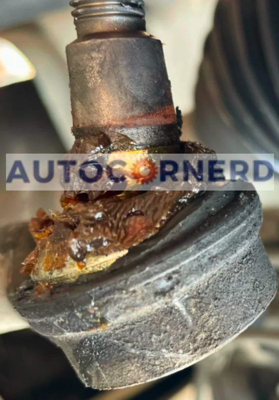 Close-up of a deteriorated suspension bushing or ball joint with visible rust and degradation, potentially leading to a clicking noise when the vehicle turns.