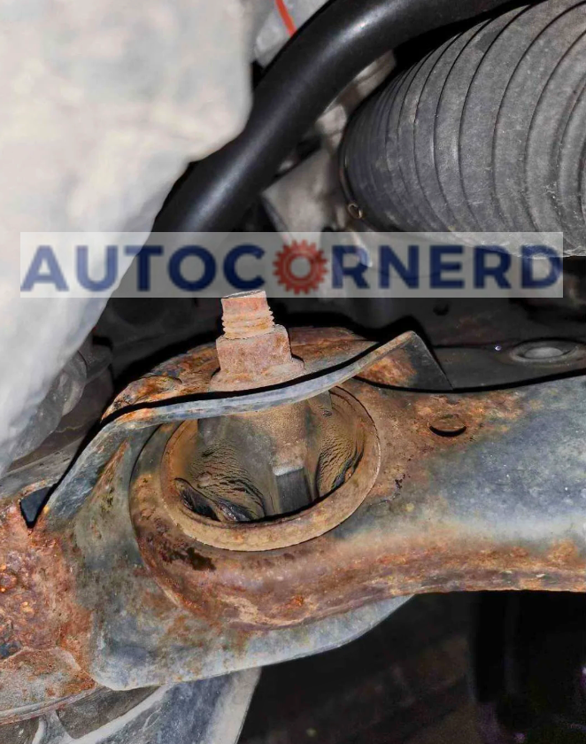 A close-up view of a damaged control arm bushing in a vehicle's suspension system, showing signs of wear and corrosion, a potential source of groaning noise when braking at low speeds.