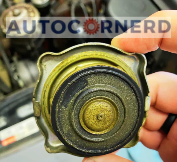 A close-up view of a person holding a loose gas cap, showcasing the intricate details of its inner side. The cap is visibly worn and covered with a layer of dust and grime, indicating potential issues that could trigger the check engine light in a vehicle